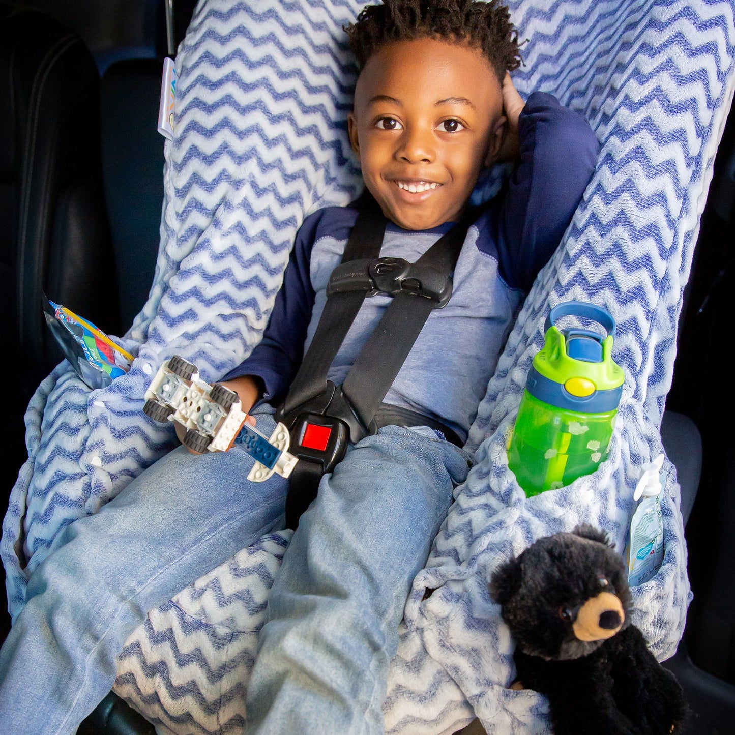 Blue chevron plush NIKO on a Graco car seat and a child holding lego